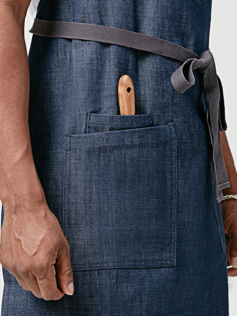 Close up Helt's Raw Bar Denim Chef Apron lap pockets holding wooden tongs.
