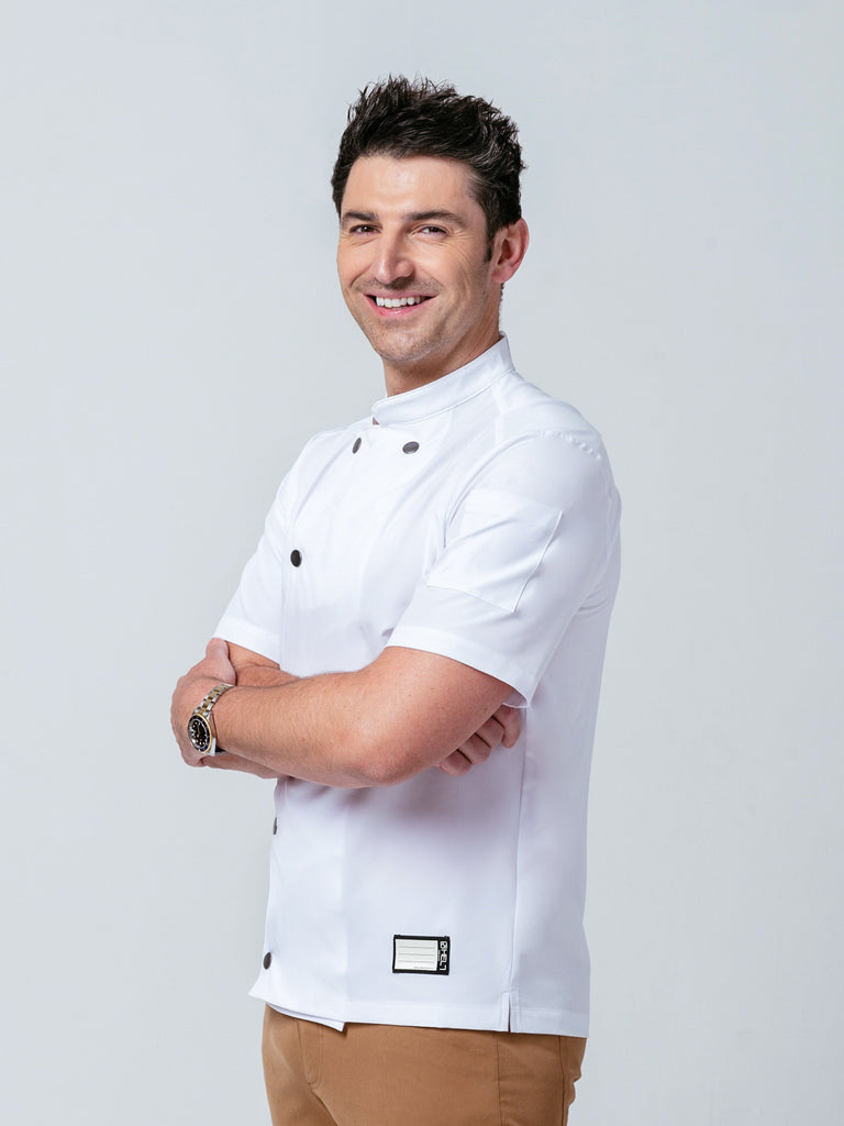 Man posing with his arms crossed modeling Helt Studio's Midtown Chef Coat in white.