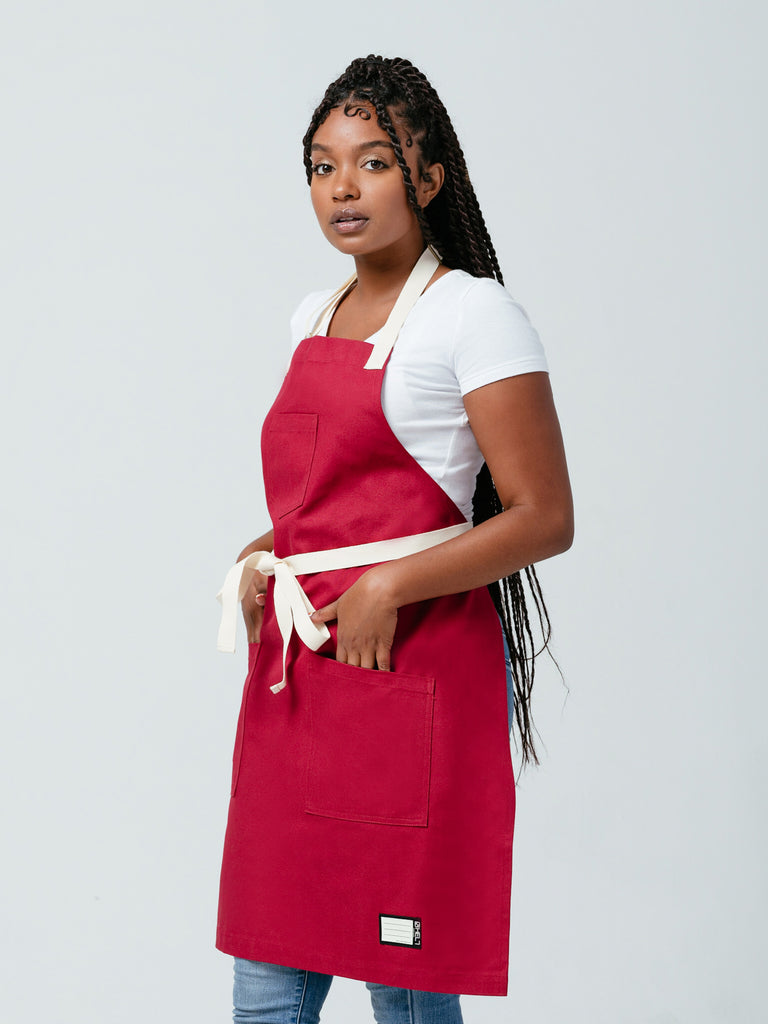 Woman posing with hands in her lap pockets modeling Helt's Burgundy Red Bib Apron.