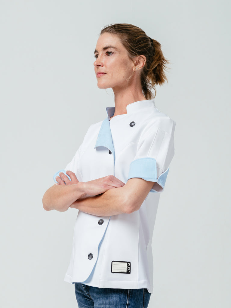 Woman posing with arms crossed modeling Helt Studio's Stephany Chef Coat in white.