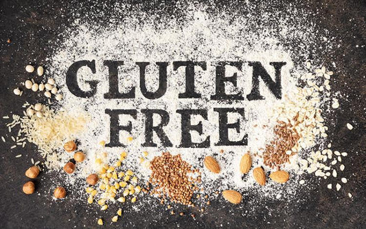 Person wearing apron adding gluten-free flour to baking tin surrounded by ingredients