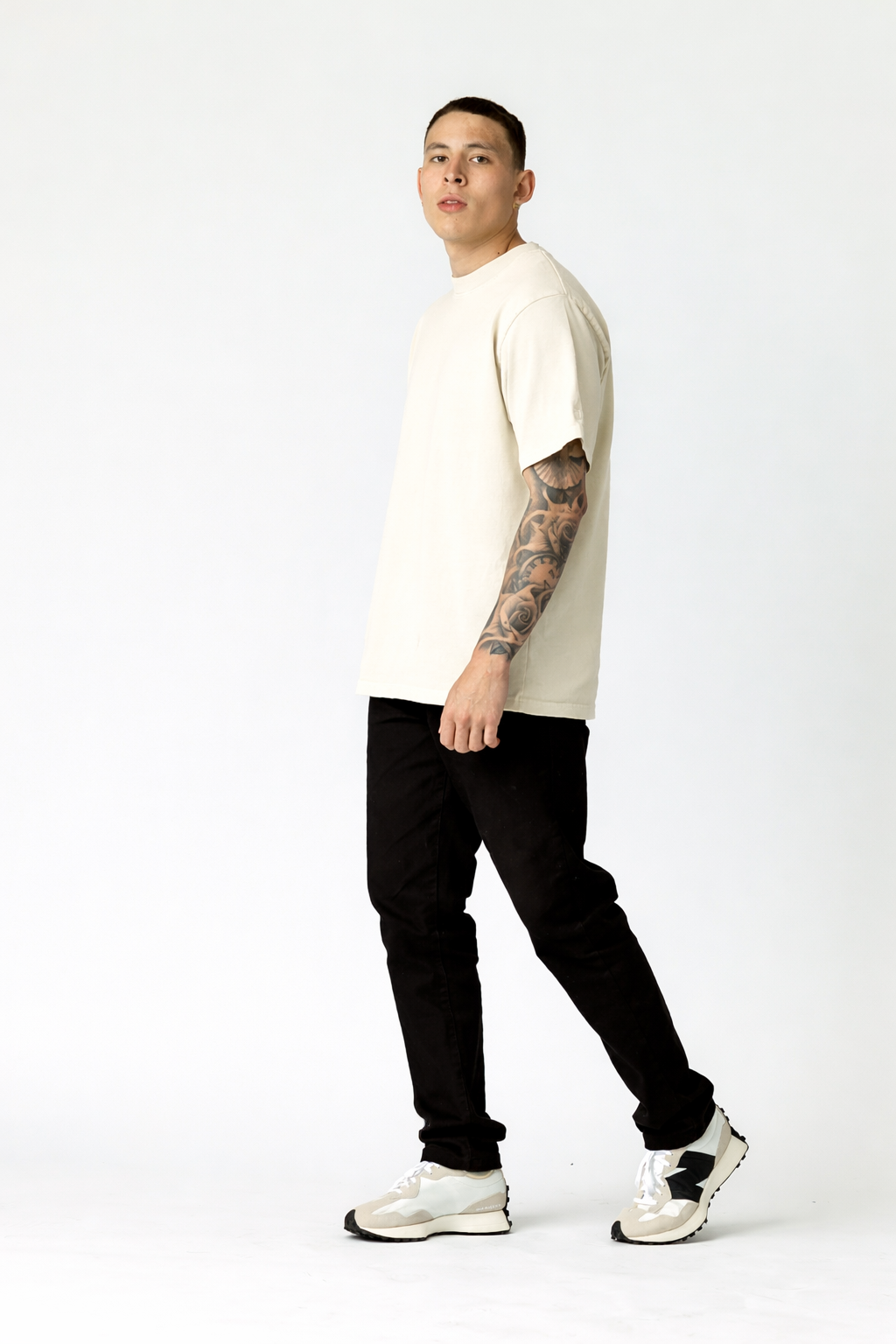 Man wearing a white t-shirt, black pants, and white sneakers on a white background