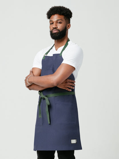 Man posing with his arms crossed modeling Helt Studio's Deep-Sea DWR Bib Apron.