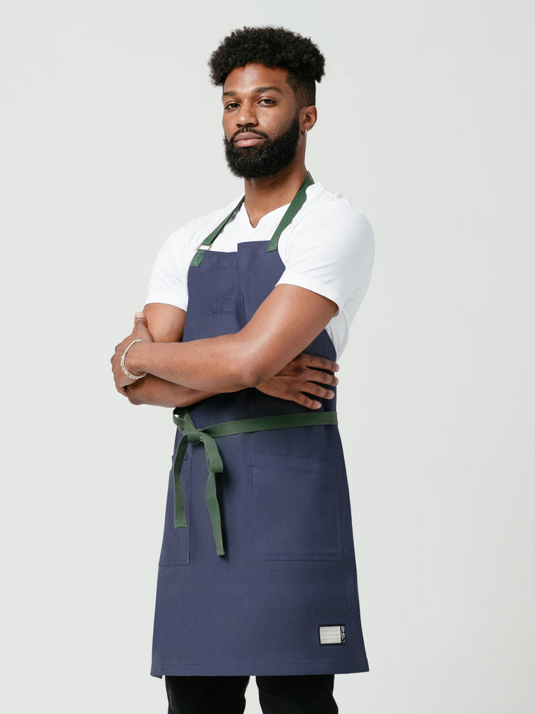 Man posing with his arms crossed modeling Helt Studio's Deep-Sea DWR Bib Apron.