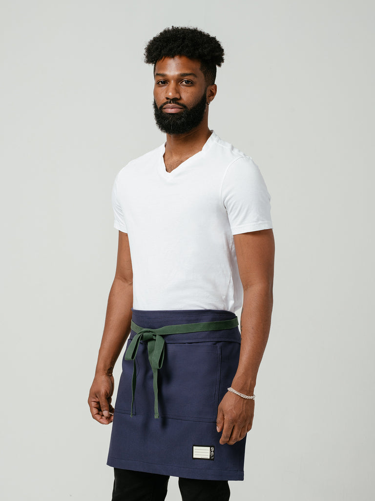 Man posing at an angle modeling Helt Studio's Deep Sea Navy Blue Bistro Apron.