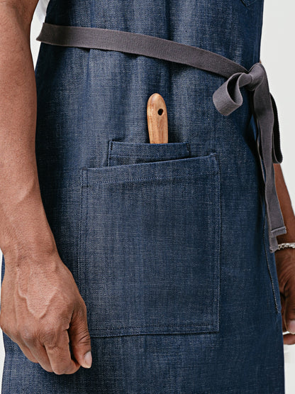 Close up Helt's Raw Bar Denim Chef Apron lap pockets holding wooden tongs.