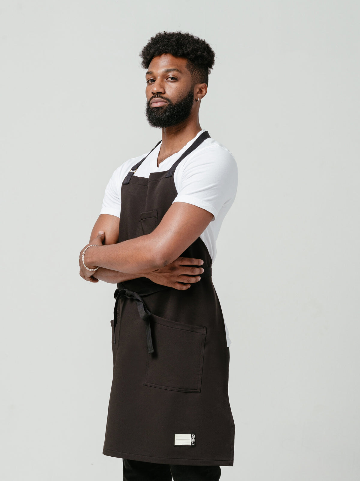 Man posing at a left angle modeling Helt Studio's Noir CrewTech Apron.