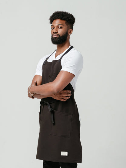 Man posing at a left angle modeling Helt Studio's Noir CrewTech Apron.