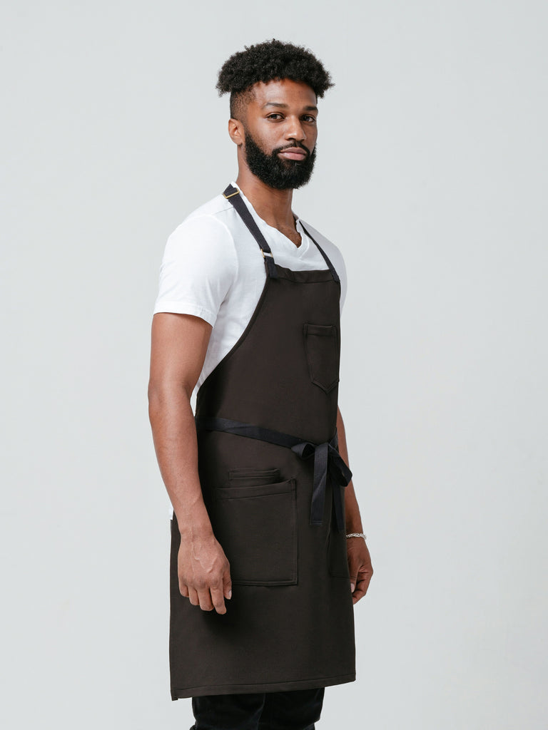 Man posing at a right angle modeling Helt Studio's Noir CrewTech Apron.