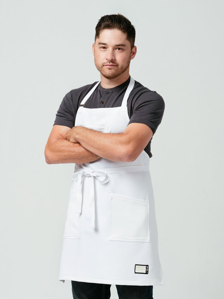 Man posing with his arms crossed modeling Helt Studio's Alpine Crewtech Bib Apron.