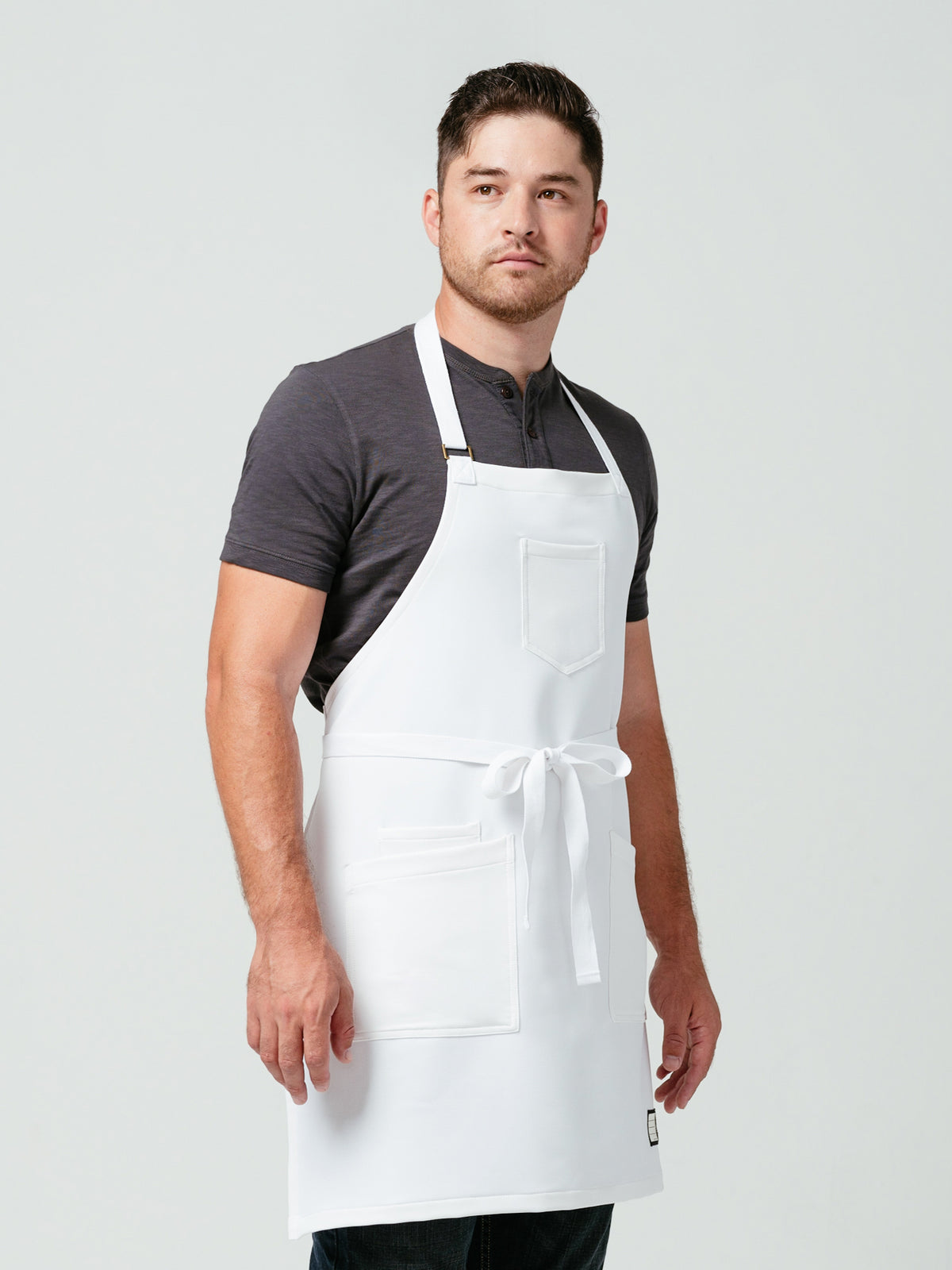 Man posing at an angle modeling Helt Studio's Alpine Crewtech Bib Apron.