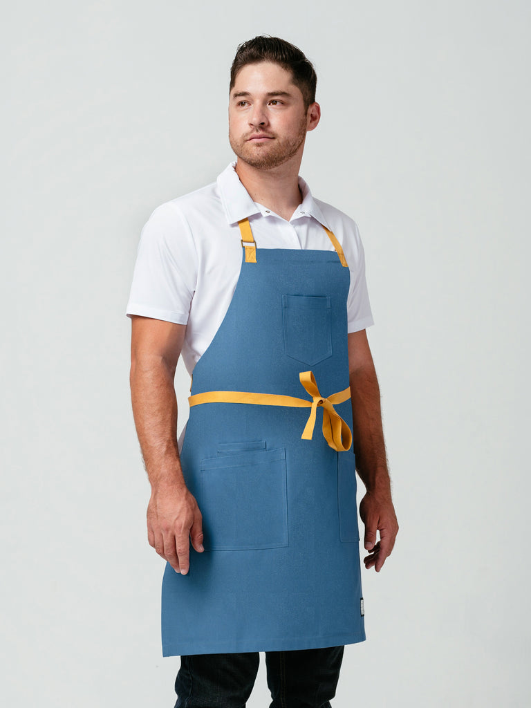 Man posing at an angle modeling Helt Studio's Pot of Gold Bib Apron.