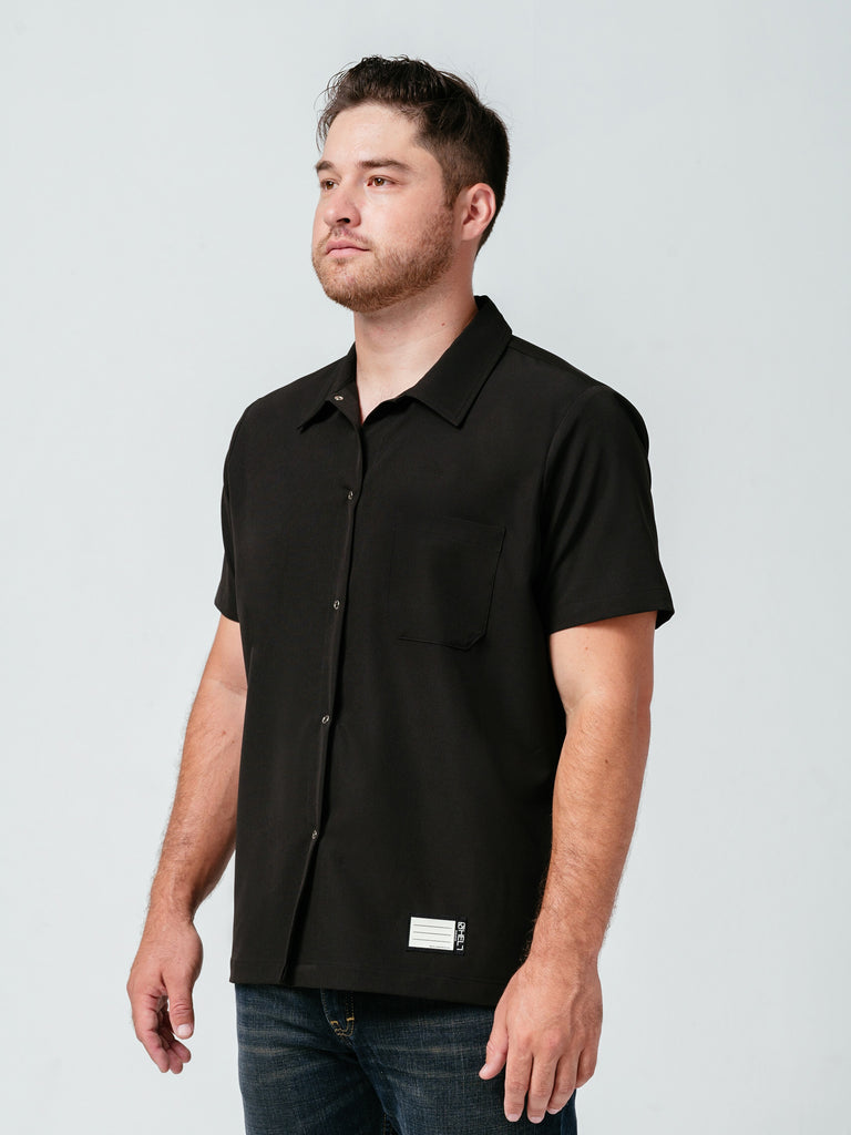 Man posing at an angle modeling Helt Studio's Utility Work Shirt in black.