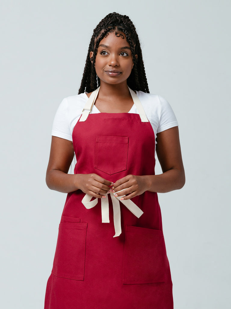 Woman looking away from camera modeling Helt Studio's Burgundy Red Bib Apron.