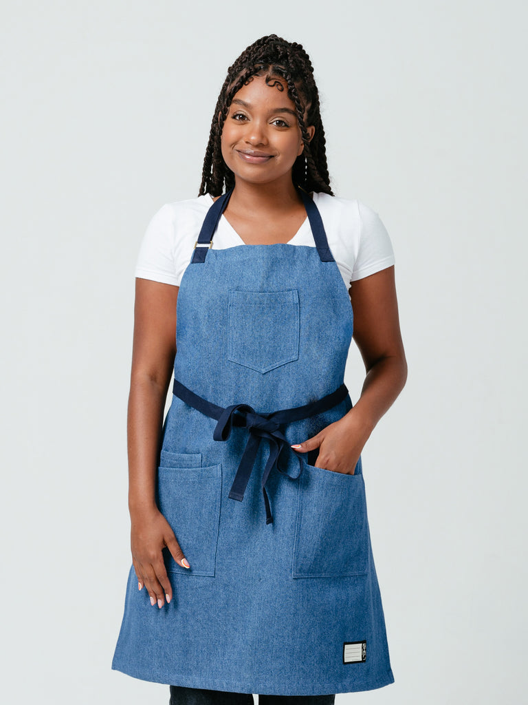 Woman placing a hand in her pocket modeling Helt Studio's Ocean Breeze Denim Apron.