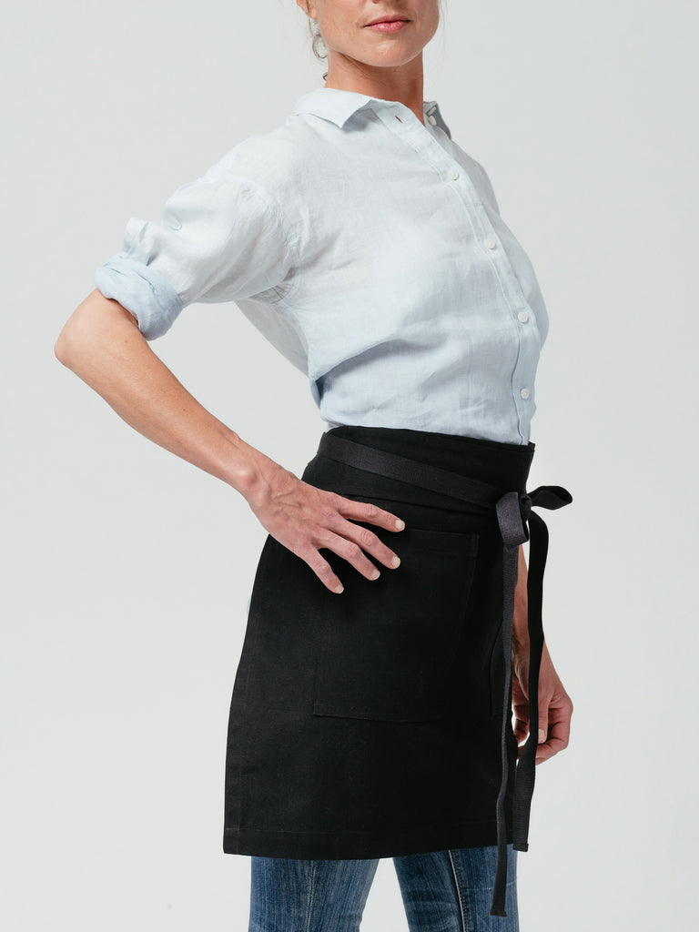 Woman with hand on her hip modeling Helt Studio's Raven DWR Bistro Apron.