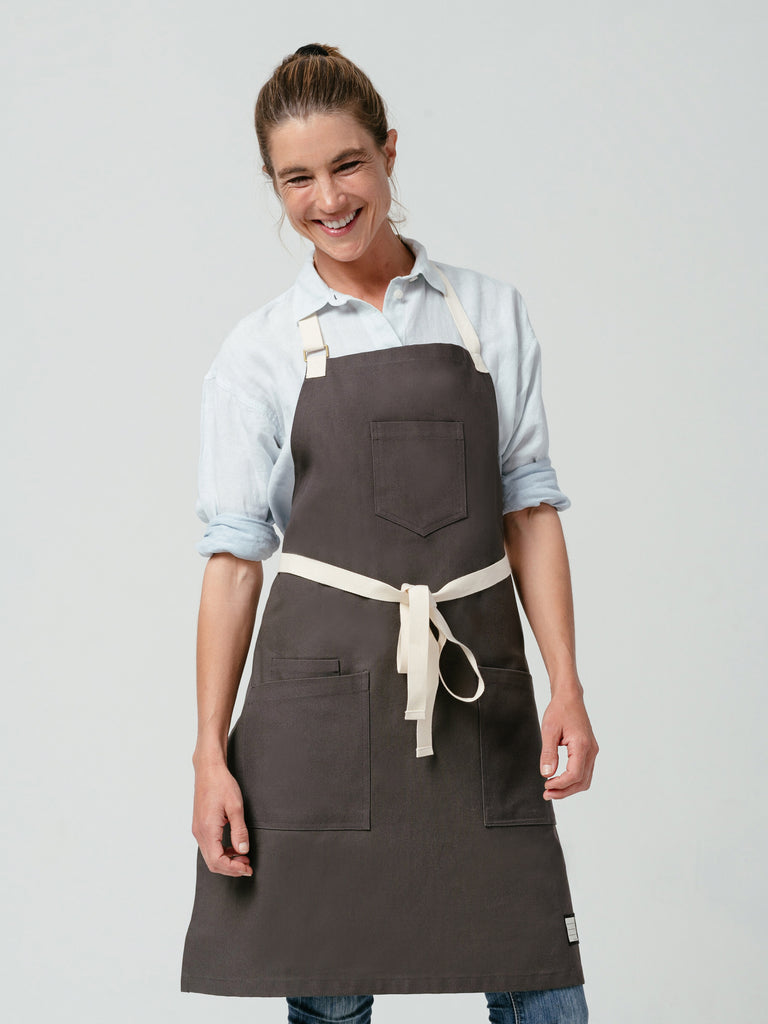 Woman laughing, modeling Helt Studio's Hardwood Briquette Bib Apron.