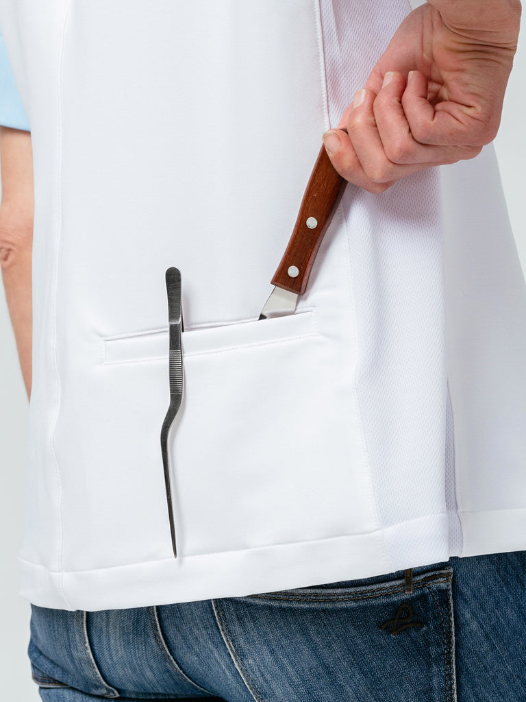 Close-up of woman placing utensils in rear pocket of the Stephany Chef Coat in white.